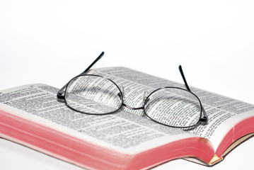 Selective focus of eye glasses on Bible