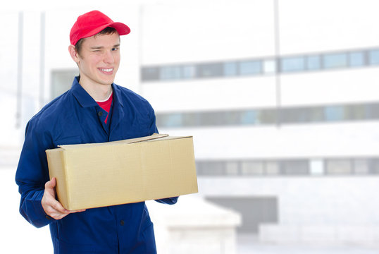 Young smiling courier holding cardboard box