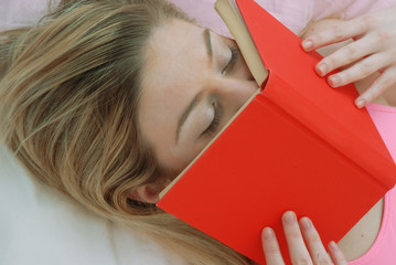Joven mujer recostada leyendo un libro.apasionada,enamorada.