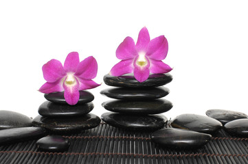 pink orchid with stacked of stones on bamboo stick straw mat
