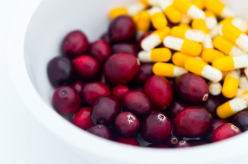 Medical mix of yellow-white pills and fresh cranberries
