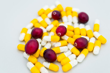 Medical mix of yellow-white pills and fresh cranberries