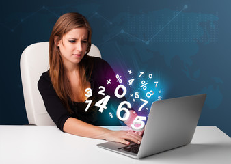 Beautiful young woman sitting at desk and typing on laptop with