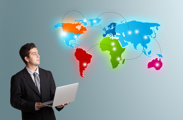 young man holding a laptop and presenting colorful world map