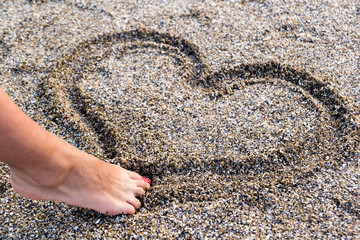 Young Girl Drawing A Heart In The Sand