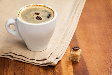 dark espresso in a cup and two beans