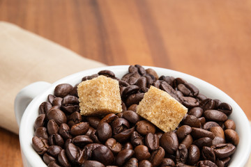 heap of coffee beans in cup with cane-sugar