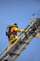 Firefighter ascends upon a one hundred foot ladder.