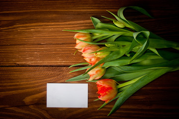 Tulips and blank card on old wooden boards