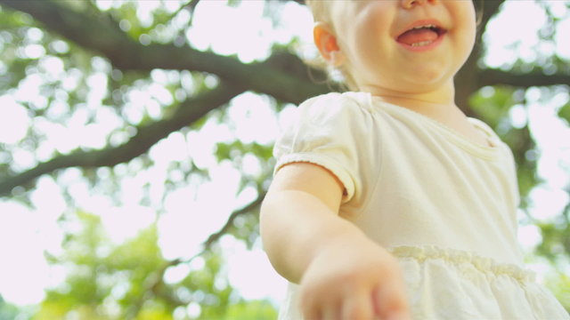 Close up of little Caucasian kid toddling in green garden