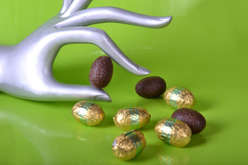 Main argentée choississant un oeuf en chocolat