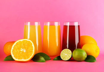 Glasses of juise with leafs and fruits on pink background