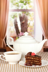 Teapot, cup of tea and delicious cake on window background
