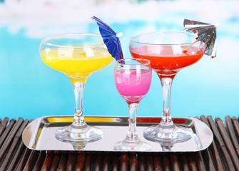 Glasses of cocktails on table near pool