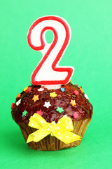 Birthday cupcake with chocolate frosting on background