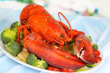 Red lobster on platter with vegetables on table close-up