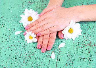 Woman hands with pink manicure and flowers, on color background