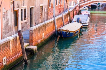 Venetian canal with boats parked around