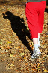 Woman walking cross country trail in autumn forest