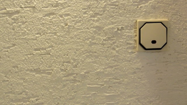 Moderner Lichtschalter mit Beleuchtung auf Rauputzwand