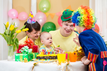 baby girl celebrating first birthday with parents and clown