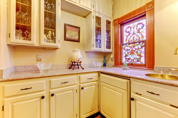 White kitchen pantry with antique cabinets and window.