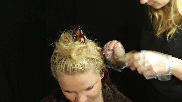 Woman and female hairdresser coloring her hair with brush