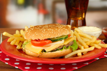 Tasty cheeseburger with fried potatoes and cold drink,