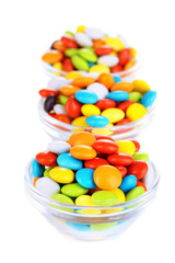 Colorful candies in glass bowls isolated on white