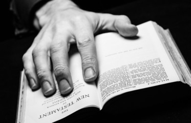 Naklejka premium A man reading the Holy Bible with one hand.