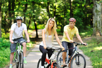 Fototapeta na wymiar Portret atrakcyjne młoda kobieta na rowerze i dwóch mężczyzn w blu
