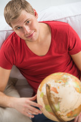 Portrait of a handsome young man sitting at home with globe and