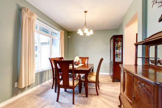 Green dining room interior with classic brown furniture.