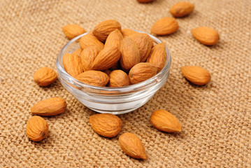 Dried almonds on glass bowl on canvas background