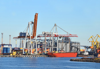 Obraz premium Container stack and ship under crane bridge