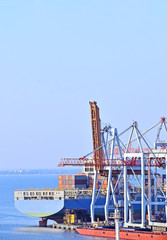 Fototapeta premium Container stack and ship under crane bridge