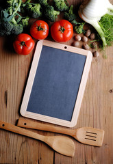 lavagna con ortaggi e cucchiai di legno