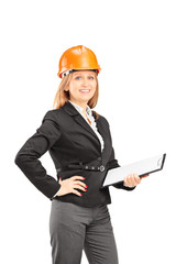 Female engineer with a helmet holding a clipboard and posing