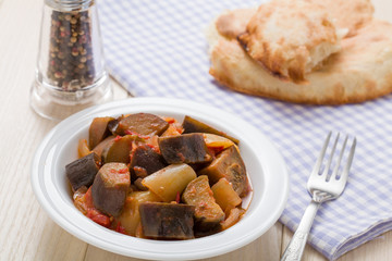 Cooked stewed eggplants in plate served with bread on table