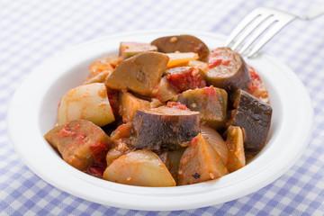 Cooked stewed eggplants in plate close-up served on linen napkin