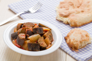 Cooked stewed eggplants in plate served with bread on table