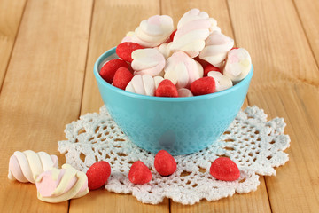 Gentle marshmallow in glass vase on wooden table close-up