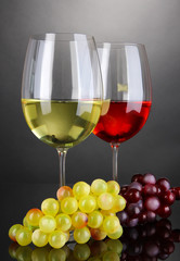 Red and white wine in glasses on grey background