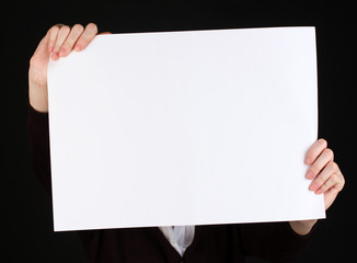Woman holding blank sign in front her face, isolated on black