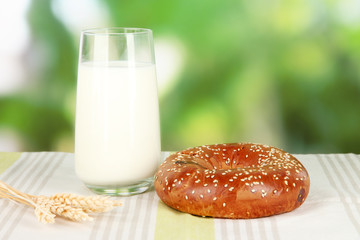 Bread roll and glass of milk on nature background