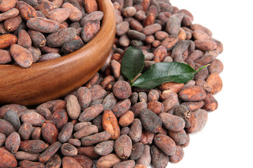 Cocoa beans in bowl with leaves, isolated on white