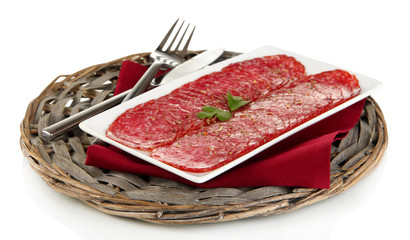 Tasty salami on plate on  wicker cradle isolated on white