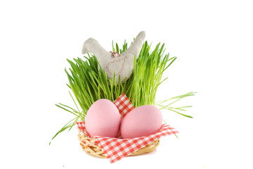 two pink eggs in basket and tuft of grass with textile bird