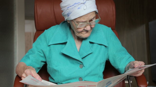 old woman sitting on chair and reading newspaper