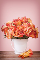 A bouquet of vintage roses in a white metal pot